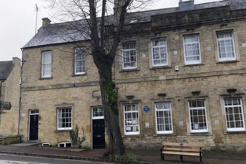 A stone building with multiple windows and a tree in front. 5