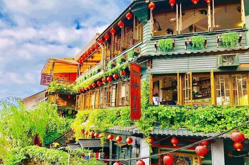 A traditional building with green vines, red lanterns, and a red banner. 5