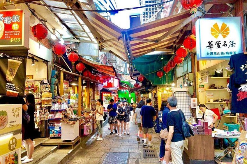 A bustling indoor market with various stalls and red lanterns. 2