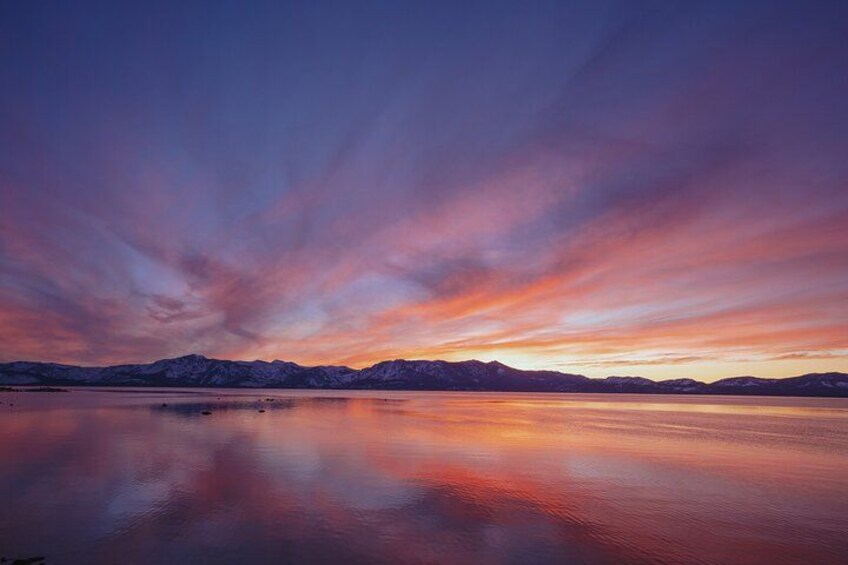 A mountain range at sunset with a calm lake reflecting the sky. 3