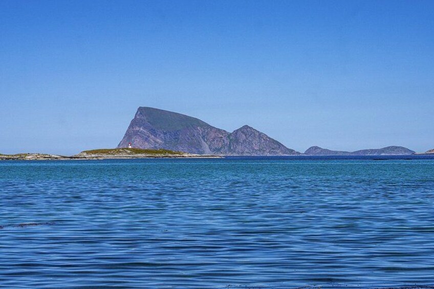 A calm sea with a rocky island and mountains in the background. 5
