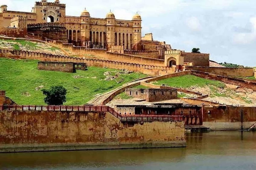 A historic fort with a large central building, a surrounding wall, and a river in the foreground. 2