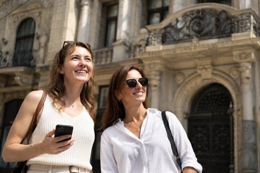 Two people standing in front of a historic building with ornate architecture. 2