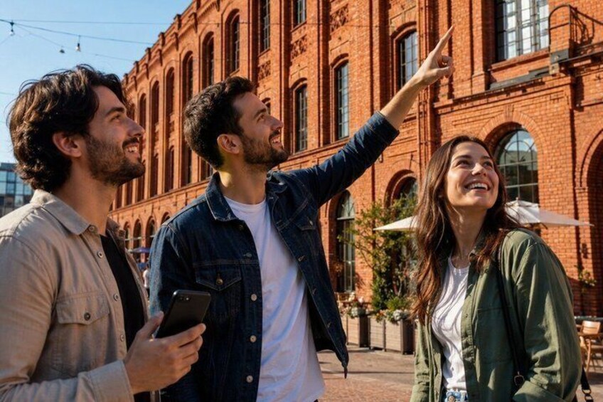 Three people standing in front of a red brick building with arched windows. 4