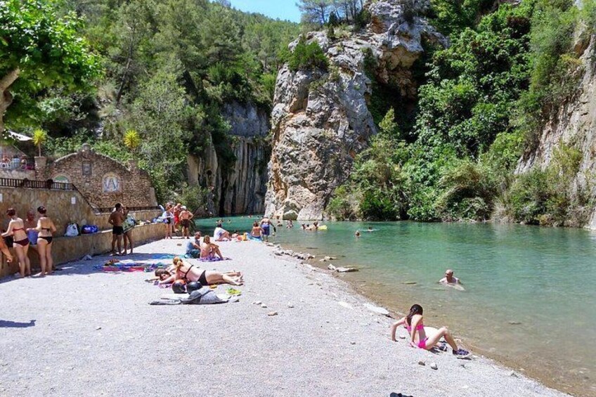 A beach with people sunbathing and swimming in the water. 2