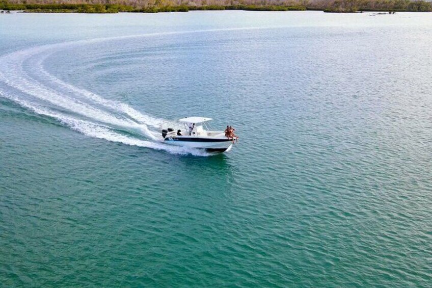 A speedboat with two people on board moving across a calm body of water. 1