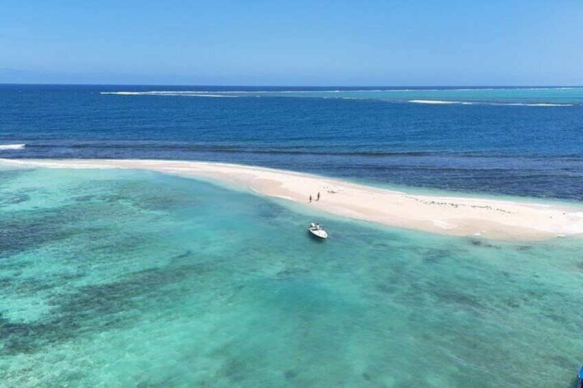 A beach with clear turquoise water and a boat on the shore. 4