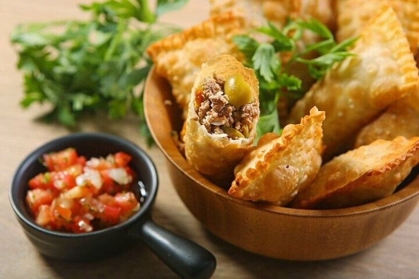 Eine Schüssel frittierter Backwaren, aus denen ein Stück herausgebissen wurde, garniert mit Petersilie, dazu eine kleine Schüssel Salsa. 5