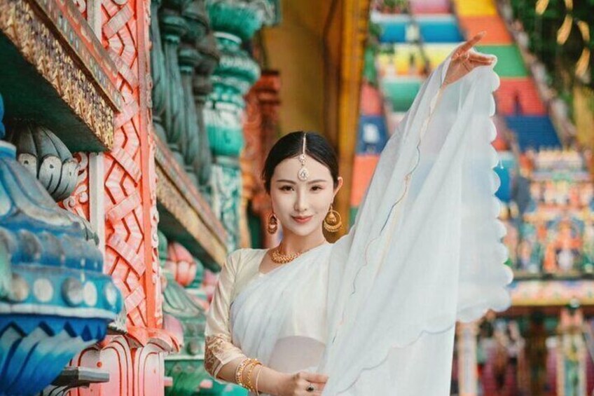 Een persoon in traditionele kleding staat op een kleurrijke markt met diverse textielpatronen. 4