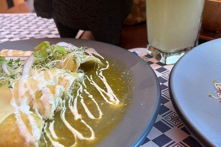 Un plato de comida con salsa cremosa y un vaso de una bebida transparente sobre una mesa. 3