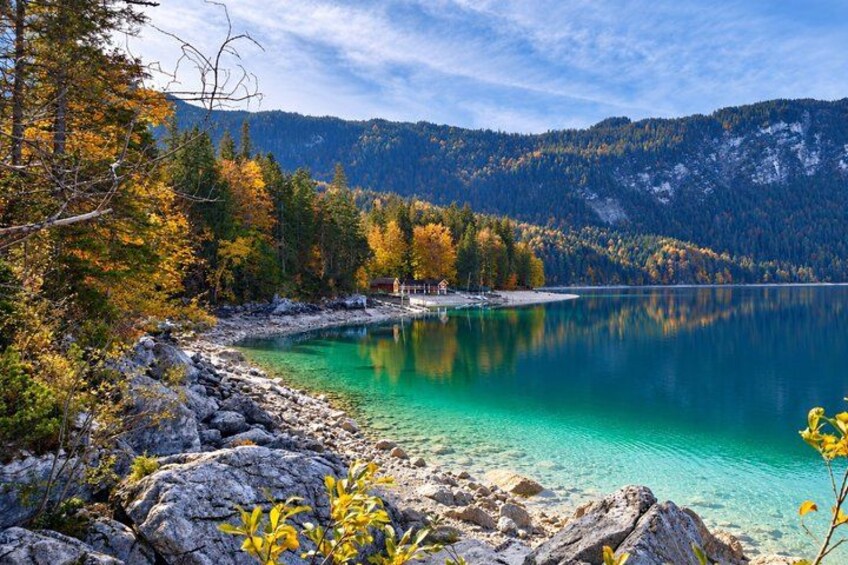 Un lac bordé d’arbres aux couleurs automnales, une rive rocheuse et des montagnes qui se dessinent à l’horizon. 3