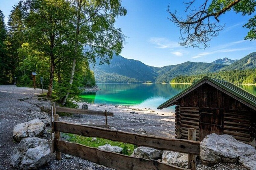 Une cabane en bois située au bord d’un lac, entourée d’arbres et de montagnes. 4