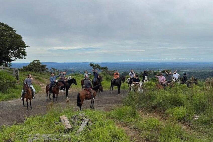 A group of people riding horses on a dirt path with a scenic view in the background. 4