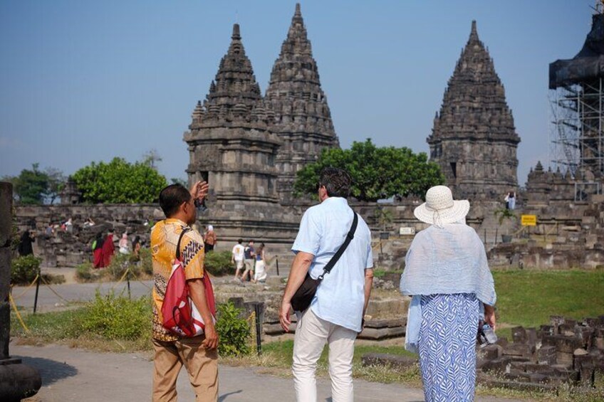 Tourists observing ancient stone structures with multiple spires. 3