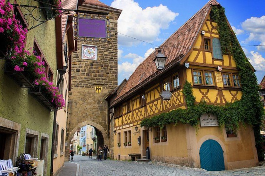 A narrow cobblestone street with traditional half-timbered houses, a stone tower, and a blue door. 4