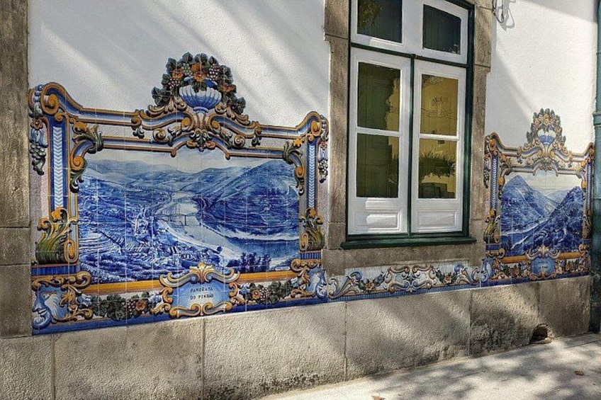 A tiled wall with a detailed landscape scene, a window, and a stone wall. 5