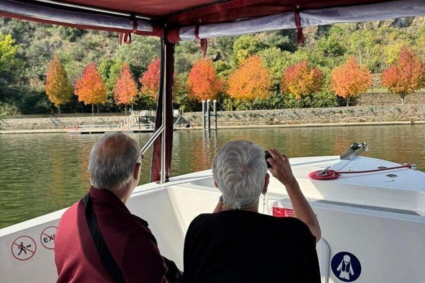 Two people on a boat, a river, and autumn-colored trees. 3