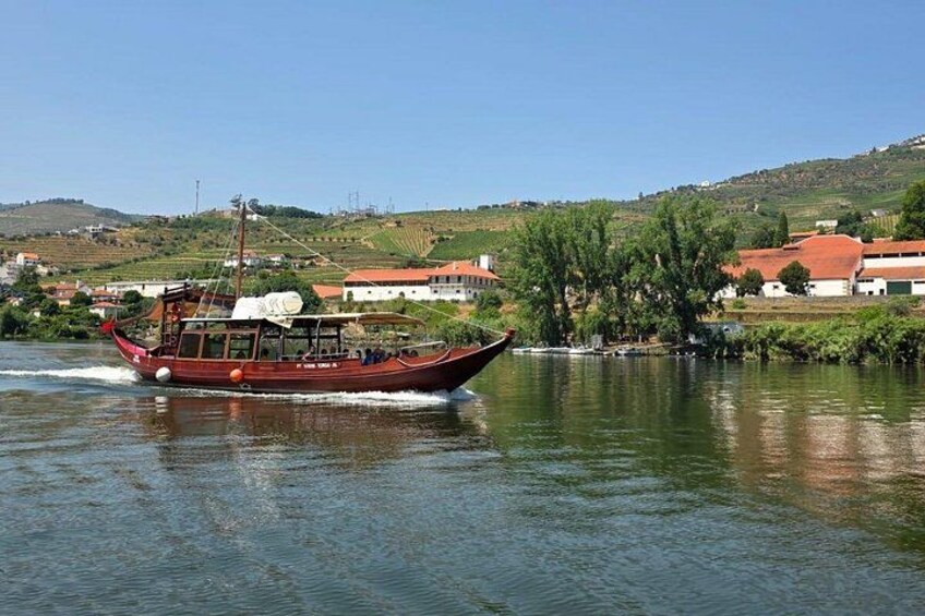 A traditional wooden boat on a calm river, surrounded by houses and greenery. 1