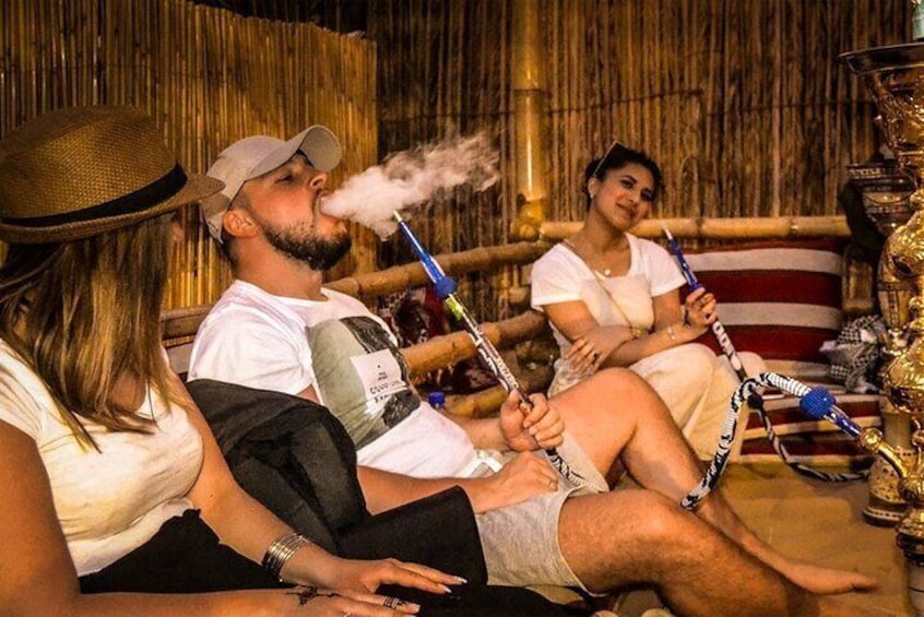 People sitting on a couch, smoking hookahs. 4