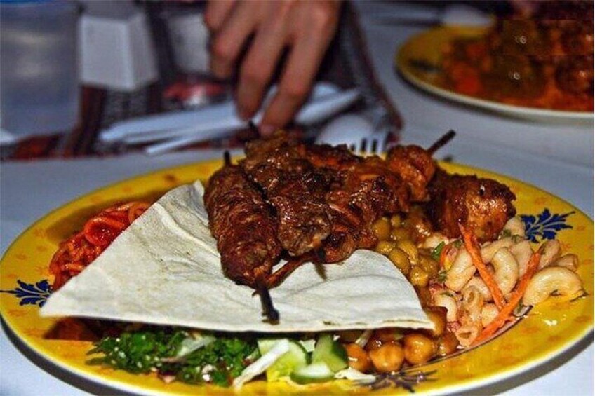 A plate of food with grilled meat, vegetables, and a flatbread. 2