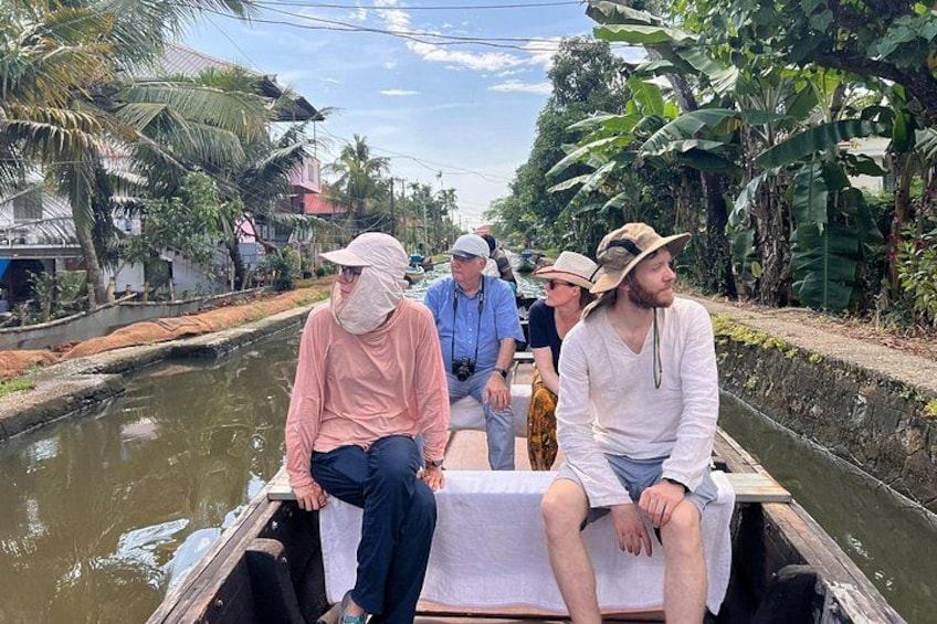 A group of people on a narrow waterway, surrounded by lush greenery and palm trees. 2