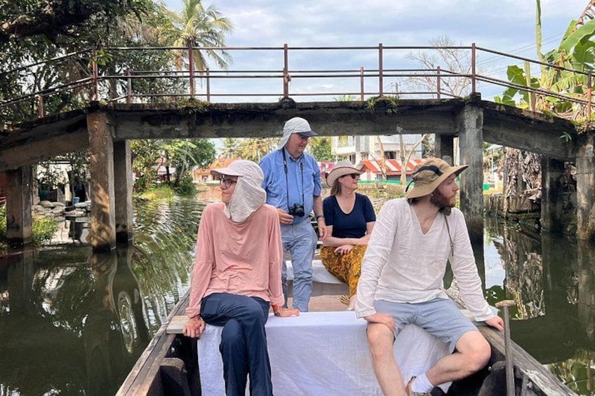 A group of people on a boat in a canal with a bridge in the background. 4