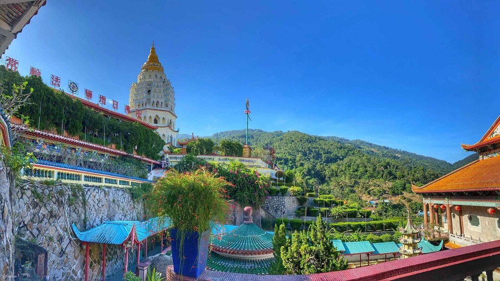 A traditional temple complex with a prominent golden spire, surrounded by lush greenery and terraced gardens. 2