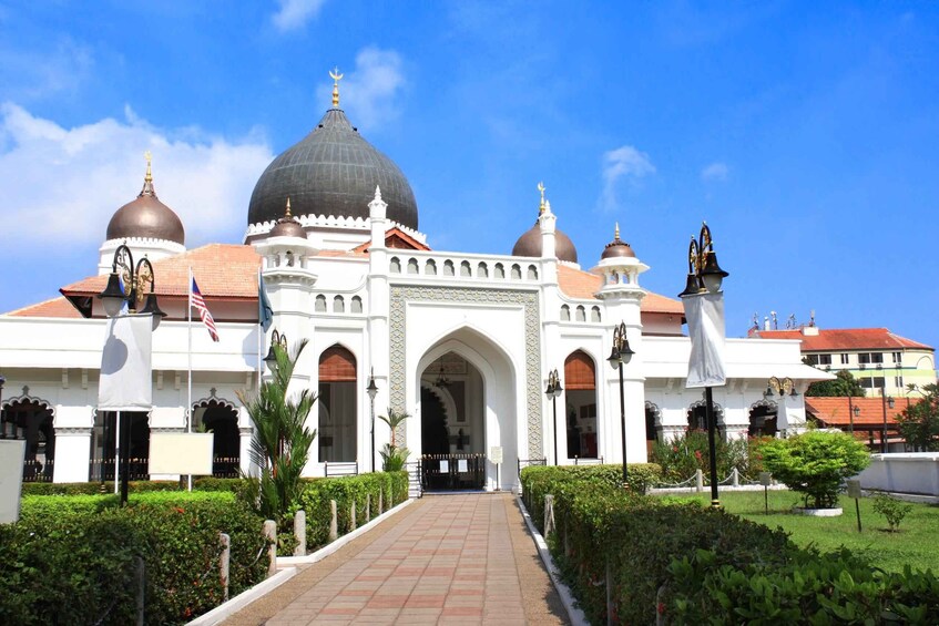 A large white building with domes and arches, surrounded by greenery. 5