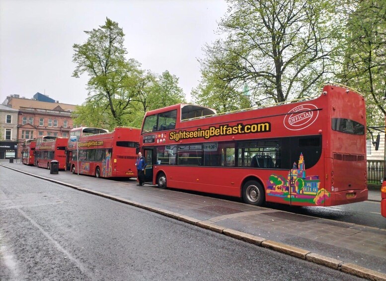 A row of red double-decker buses parked on a street. 5