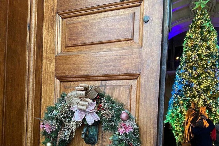 A wooden door with a wreath and a Christmas tree. 4