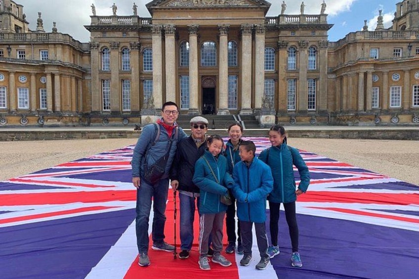 A group of people standing in front of a large building with a British flag. 1