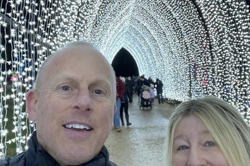 A tunnel with white lights and people walking through. 2