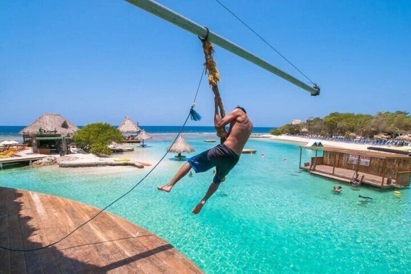 A man swinging on a rope over a turquoise ocean. 1