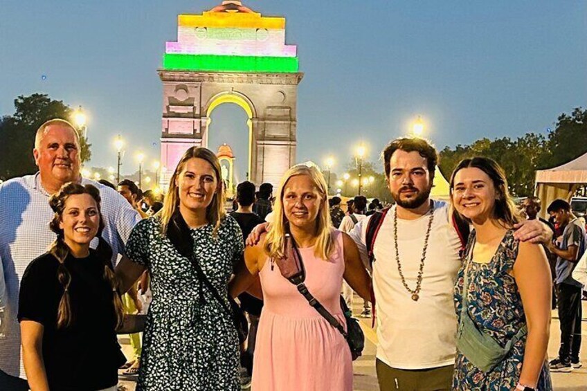 A group of people standing in front of a brightly lit monument with a colorful top. 1