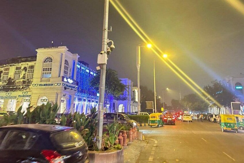 A nighttime street scene with illuminated buildings, streetlights, and vehicles. 4