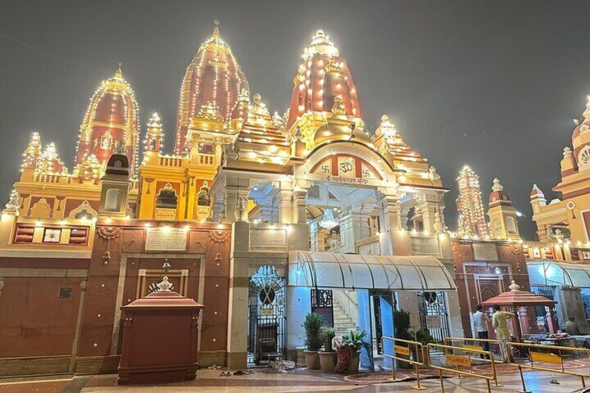 A brightly lit temple with multiple spires and a large entrance gate. 2