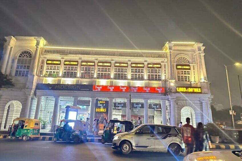 A brightly lit building with multiple storefronts, including a visible 'HIDESIGN' sign and a 'LORD DRINKS' sign. 3