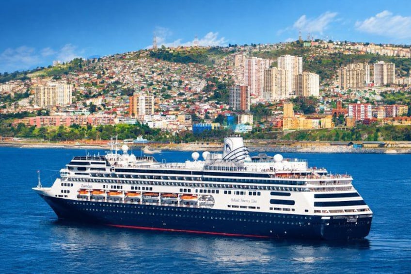 A large cruise ship with multiple decks and a cityscape in the background. 1