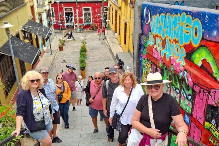 A group of people walking on a narrow street with colorful graffiti on the walls. 2