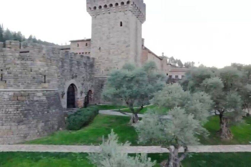 A historic stone castle with a tower, surrounded by well-maintained greenery and pathways. 3