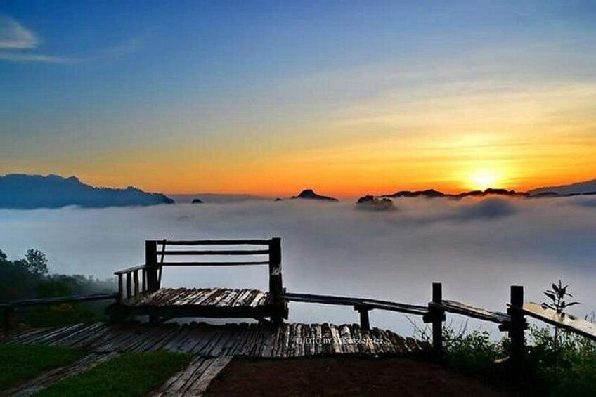A wooden bench overlooking a sunrise over a misty landscape. 3
