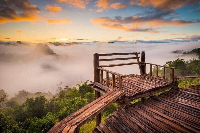A wooden observation deck overlooking a misty valley with a sunrise or sunset. 5