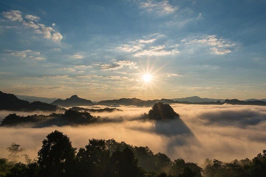 A sunrise over a mountainous landscape with clouds below the peaks. 1
