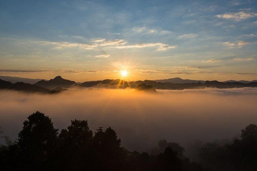 A sunrise over a misty landscape with mountains in the distance. 4