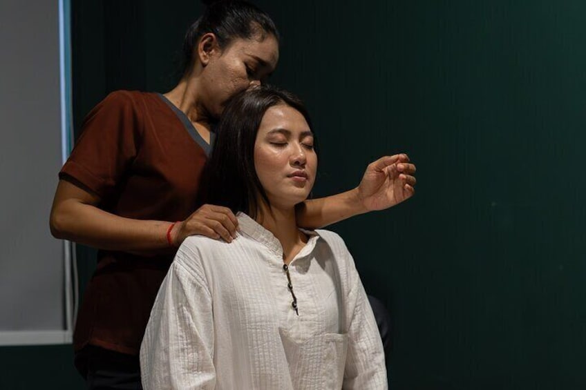 A person in a white shirt being assisted by another person in a brown shirt. 1