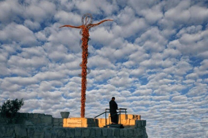 A person standing on a stone wall with a tall, twisted metal sculpture against a cloudy sky. 2