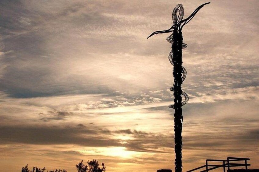 A tall sculpture against a sunset sky. 3