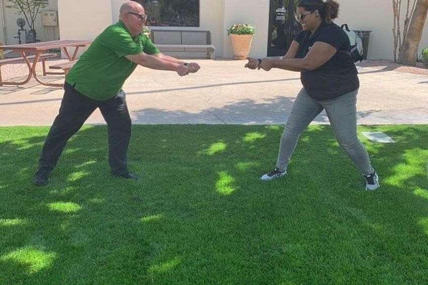 Two people playing a game of table tennis outdoors on a grassy area. 1