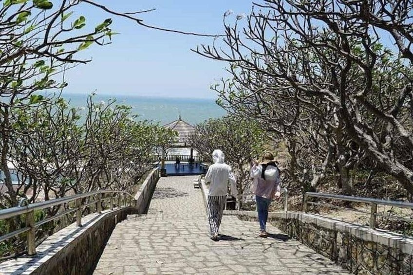 A stone pathway leading to a gazebo with a view of the sea. 2