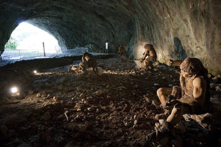 A cave with people sitting on the ground, some holding objects. 2